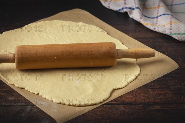 Dough is rolled out on baking paper with a rolling pin
