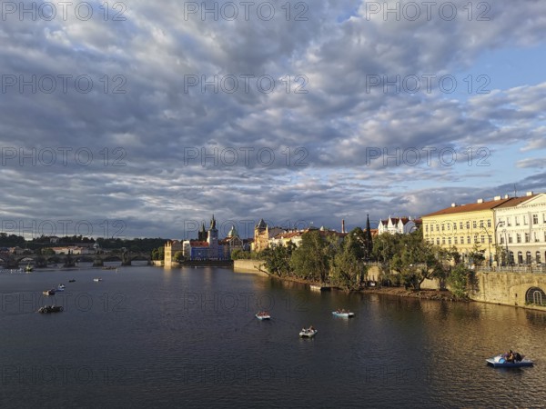 Prague in the evening sun. Vltava surrounded by illuminated historic buildings, small boats