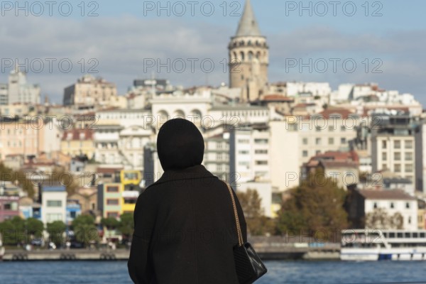 Istanbul, Turkey. November 10th 2022 A Muslim women looks out over the Golden Horn towards the
