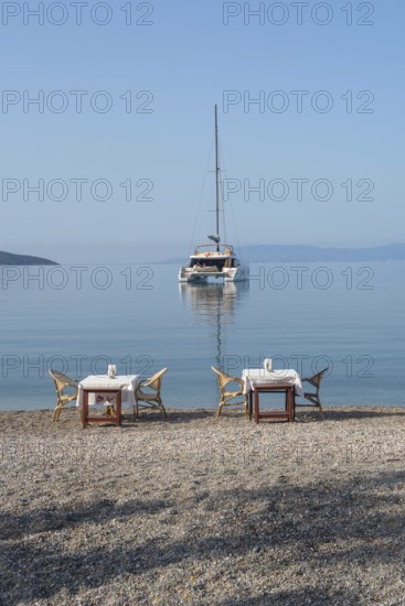 Bodrum, Mugla, Turkey. April 22nd 2022 Restaurant tables on the beach with a Catamaran moored in