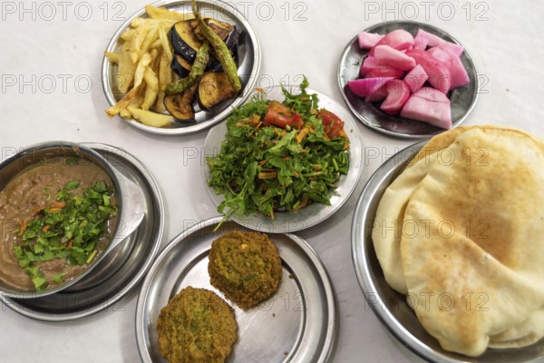 A table prepared with typical Egyptian street food of Fuul and Falafel with Salad, Pickles and