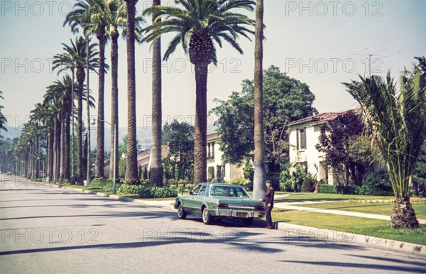 Woman standing by Chrysler Plymouth Volarét car in Beverly Hills, California, characterized by its