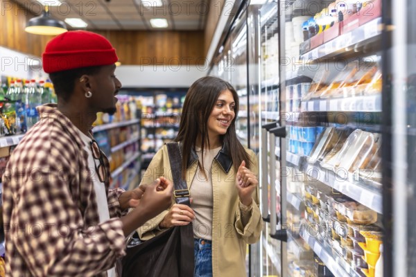 Diverse couple browsing refrigerated display at grocery store, making choices for healthy eating,