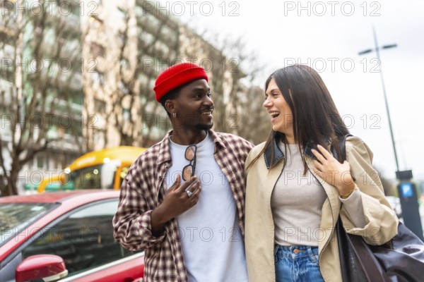 Diverse young couple walking together in an urban setting, enjoying a candid moment and sharing