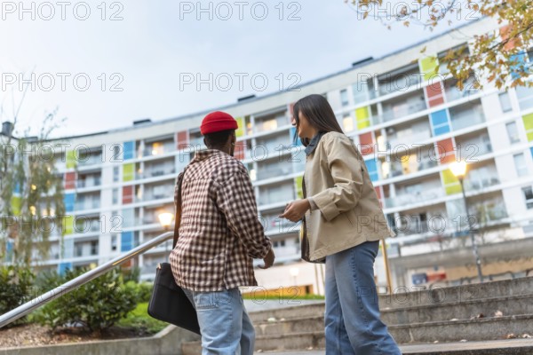 Diverse young adults walking and talking down outdoor steps in a modern urban neighborhood with a