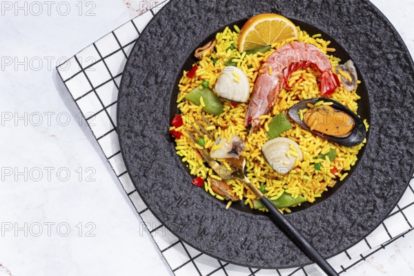 Seafood paella on a black plate, no people