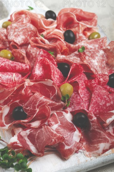 Assorted, meat appetizer, prosciutto, salami and ham, with olives, close-up, breakfast, top view,