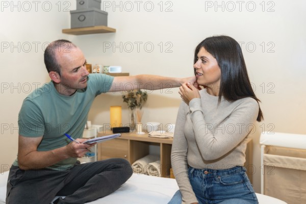 Physiotherapist consulting with a young female patient, carefully examining her neck and shoulder