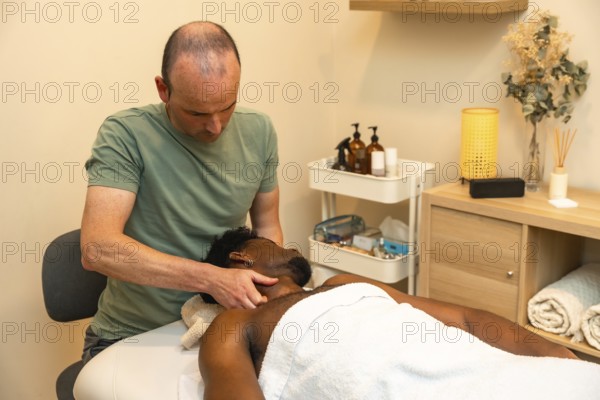 Male therapist applying therapeutic pressure to a male client's neck and shoulders on a massage