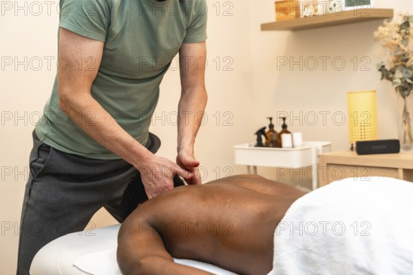 Professional therapist giving a relaxing back massage to a client lying face down on a treatment