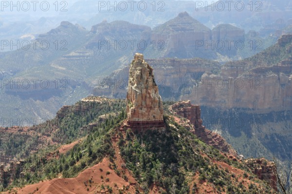 A distinctive rock formation rises in the midst of a rough and dry canyon landscape with wide