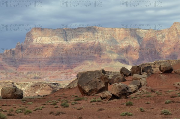 Large rocks spread across an impressive red desert landscape with dramatic skies, Grand Canyon