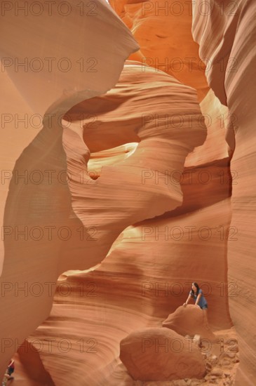 Rocky sandstone gorge in shades of orange with one person surrounded by smooth, lively rocks,