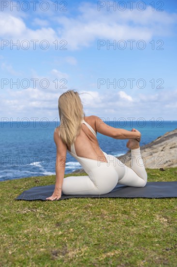 Woman practicing yoga stretch on a mat by the ocean, embracing wellness, balance and mindfulness in