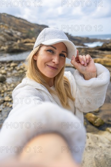 Happy woman smiling to camera and adjusting her white cap, enjoying a casual outdoor moment on a