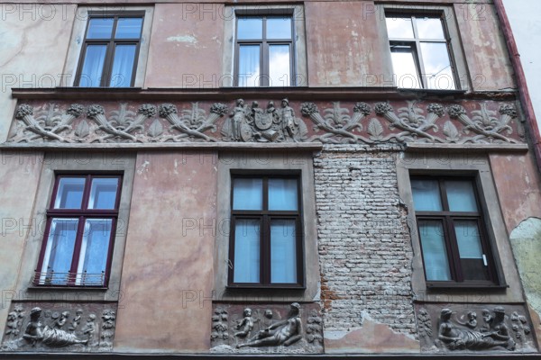 Relief band with cornucopias and figures on a dilapidated house façade from the 19th century,