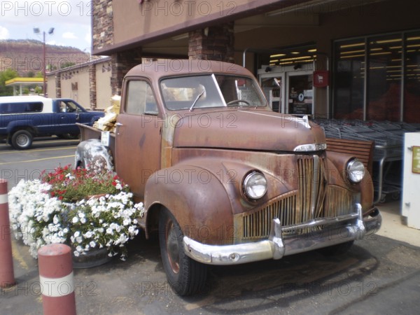 Nostalgic, rusty Studebaker pick-up truck with flower decoration in front of the Honey's