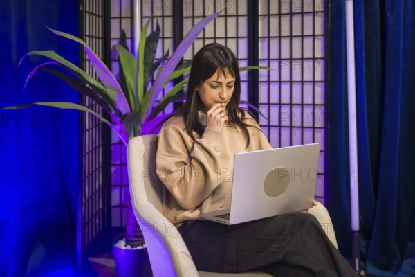 Young woman focused at a laptop in a modern studio, planning and creating social media and podcast