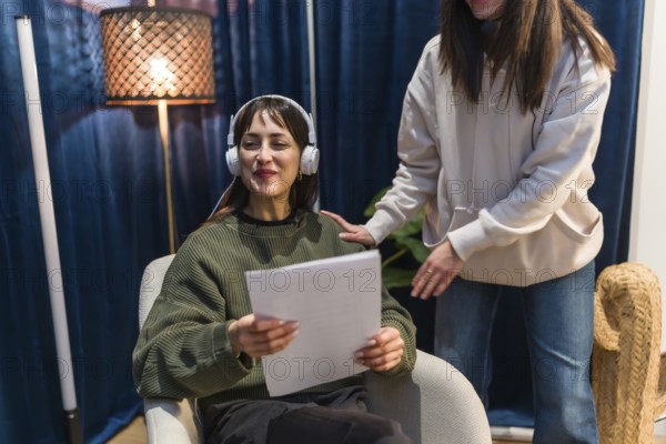 Young woman in headphones holding papers and smiling while preparing to record a podcast or social