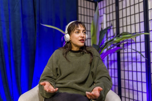 Woman wearing headphones and gesturing while speaking, creating engaging audio content for social