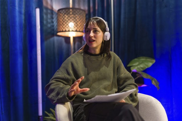 Young woman recording social media content or a podcast episode, wearing headphones and holding