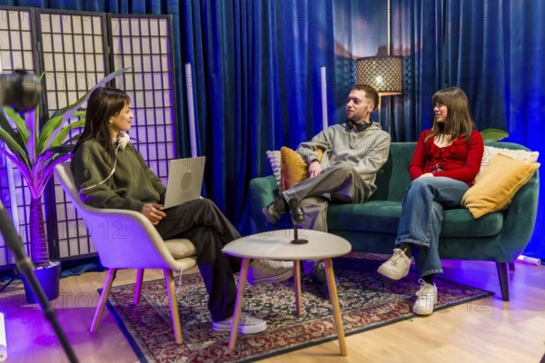 Young men and women are collaborating and talking in a colorful studio setting, recording a podcast