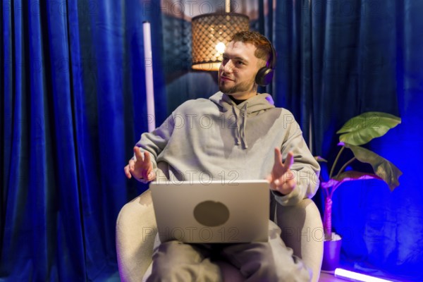 Young man wearing headphones and using laptop, recording a podcast or live streaming content from