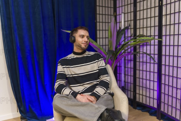 Young content creator wearing headphones, sitting in a modern studio setup, preparing for a podcast