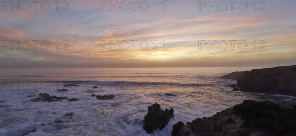 Pastel-coloured sunset over the sea. The light of the sky is reflected gently over the waves,