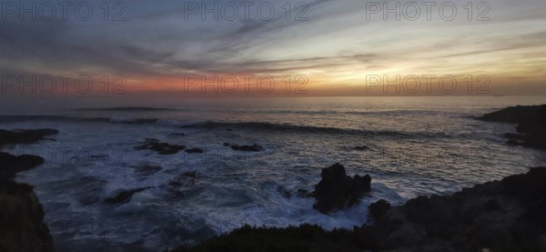 Subdued sunset with dark clouds and rocks in the sea, romantic atmosphere, hiking on the