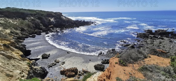 A rocky stretch of coast with a view of the blue sky and the rushing sea, hiking on the Fisherman's