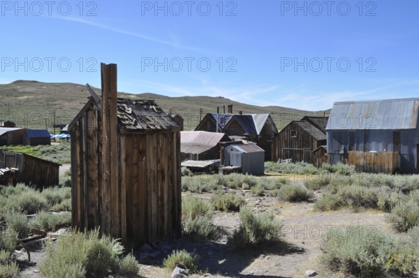 An abandoned village with several wooden houses, toilet, outhouse in the foreground, in a natural,