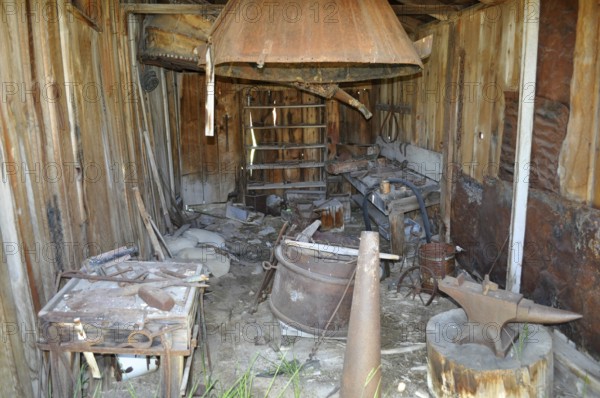 An old blacksmith workshop with rusty tools and wooden structures in an abandoned state, Bodie