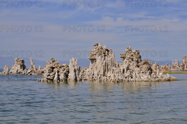 Unique rock structures, limestone formations rising from the calm water of a lake under a clear