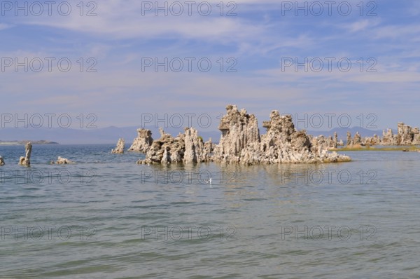 Notable rock formations, calcareous tuff formations emerging from calm water, situated under a