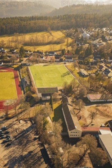 Residential area with sports ground and lots of trees in sunlight taken from the air, Wimberg,