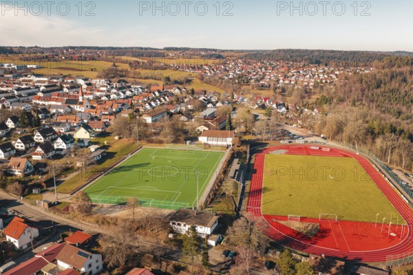 Aerial view of two neighboring sports fields in a village with soccer field and running track,