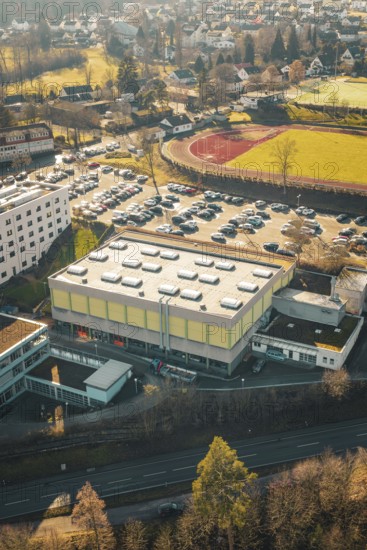 School complex with sports field and large parking lot, surrounded by winter countryside, Wimberg,