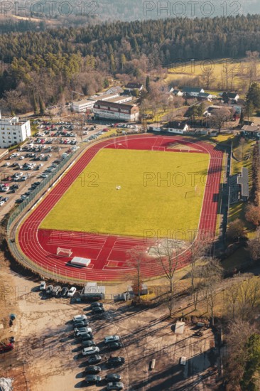 Red track with green grass and surrounding forest in a village, seen from the air, Wimberg, Calw,