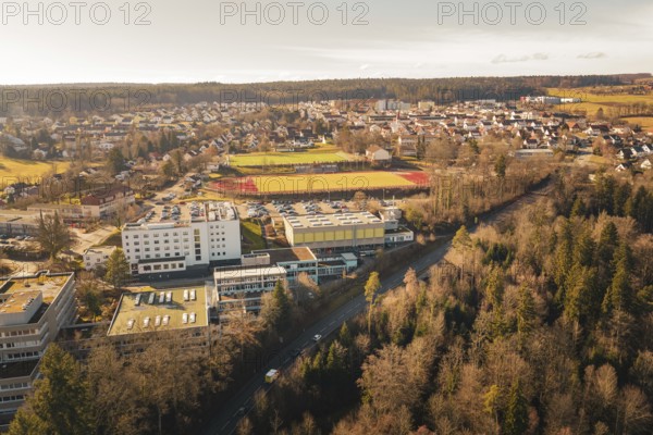 Extensive view of an urban landscape with schools, sports facilities and surrounding forests in a