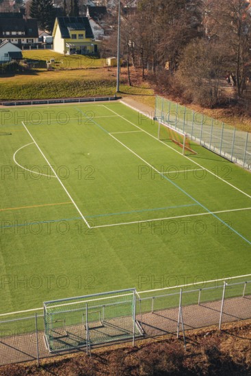 Football field surrounded by fences, lawn and trees in the background, Wimberg, Calw, Germany