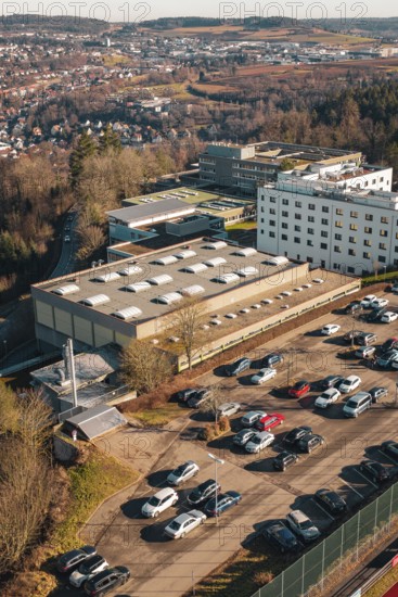 Industrial area with large buildings and lots of parked cars, wintry atmosphere, view of the city,