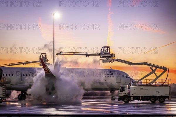 Frost at the airport in front of sunrise. A Turkish Airways aircraft is de-iced. Airbus A321-231.