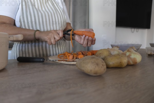 Close up of hands peeling fresh carrot in home kitchen. Healthy ingredients, simple food
