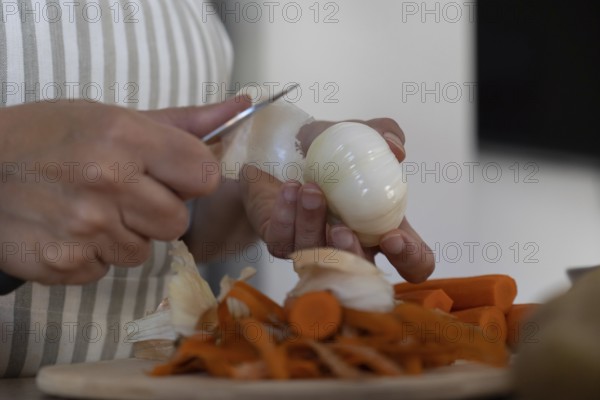 Close up of hands peeling onion for homemade meal. Simple ingredients, food preparation and