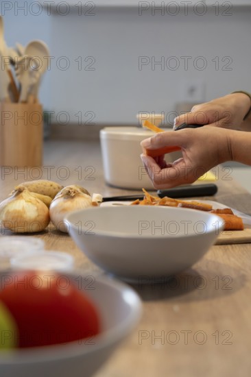 Vertical close up of hands peeling carrot over cutting board. Healthy cooking, fresh vegetables and