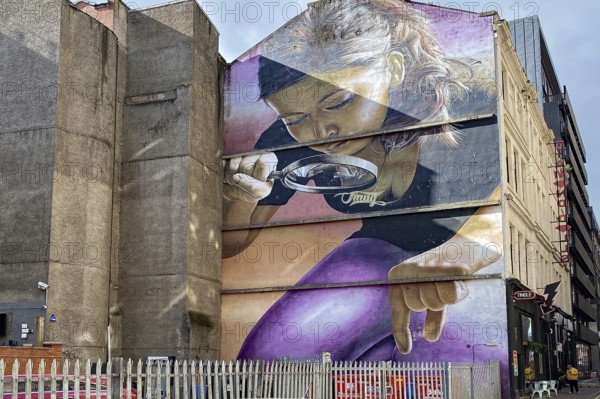 Large wall painting of a woman with magnifying glass in an urban setting, mural, street art,