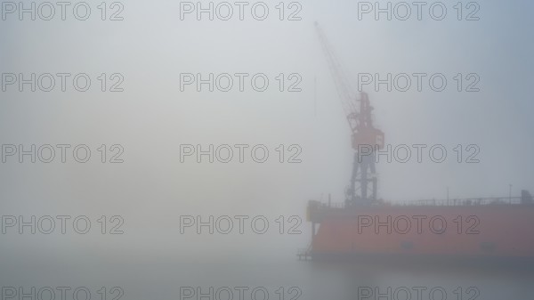 View of a dry dock at the port of America with a crane standing in fog, Cuxhaven, Lower Saxony,