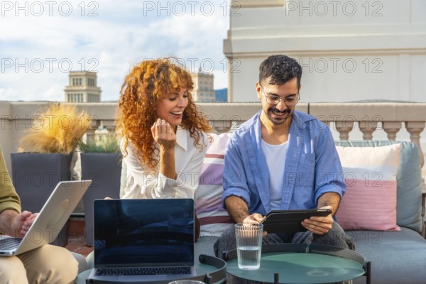 Young business colleagues working together on laptops and tablets, sharing ideas, and enjoying a