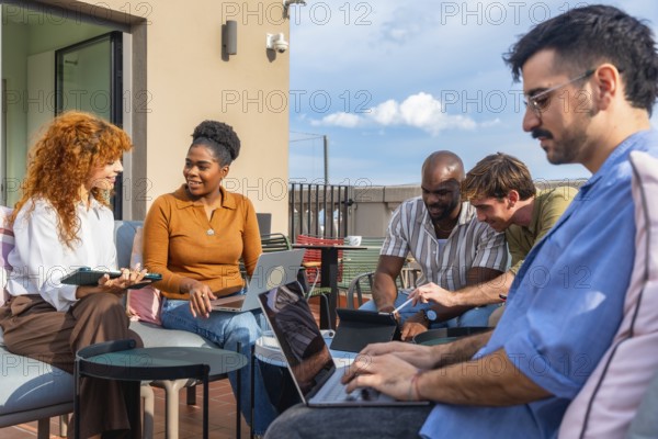 Group of diverse business people using laptops and tablets while working together on a